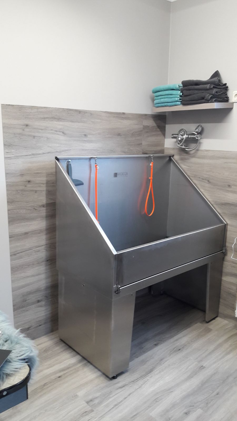 De rvs wastafel met oranje lussen, schone handdoeken op de plank erboven